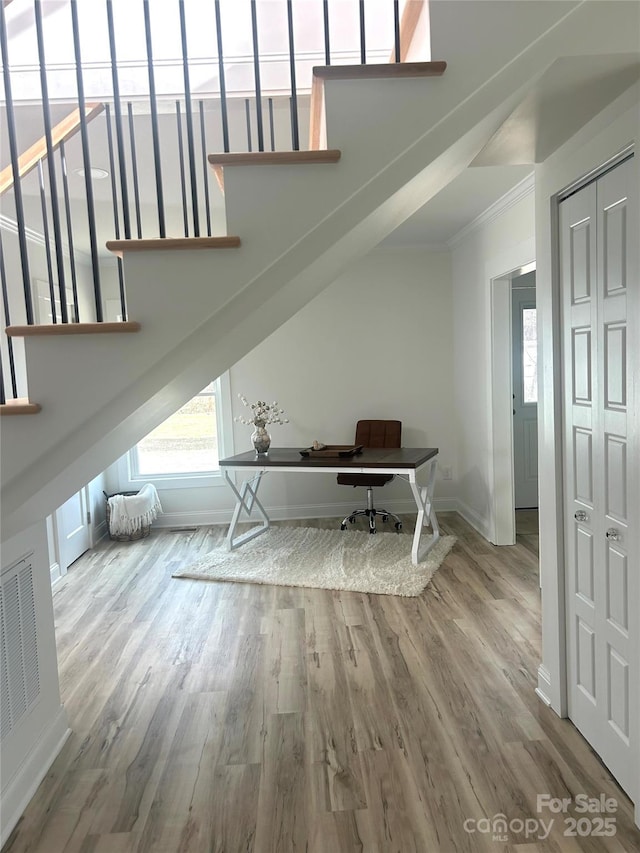 interior space featuring baseboards, wood finished floors, visible vents, and crown molding