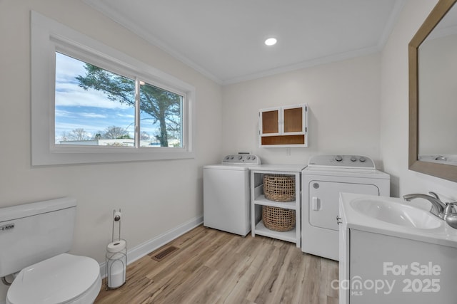 laundry area featuring laundry area, visible vents, washer and dryer, light wood-type flooring, and a sink