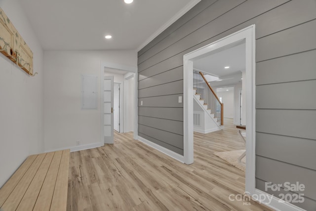 spare room with recessed lighting, wood walls, stairway, electric panel, and light wood finished floors