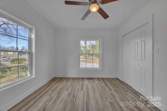 unfurnished bedroom with multiple windows, light wood-style flooring, and crown molding