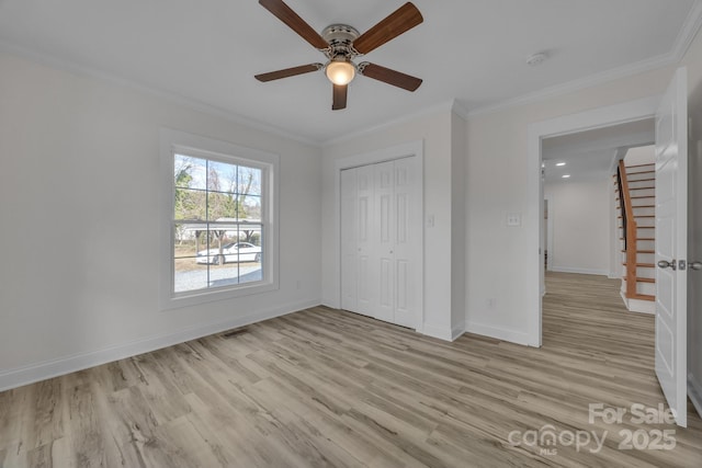 unfurnished bedroom with baseboards, ornamental molding, a closet, and light wood-style floors