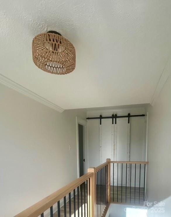 corridor featuring a textured ceiling and crown molding