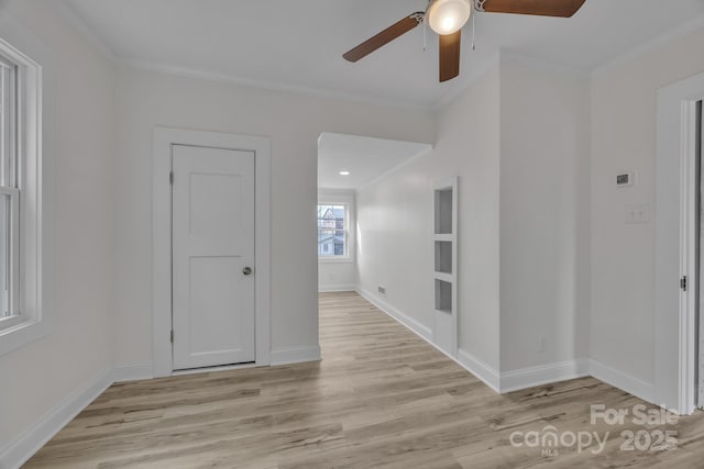 spare room with baseboards, crown molding, and light wood finished floors