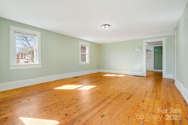 spare room with a wealth of natural light, baseboards, and light wood finished floors