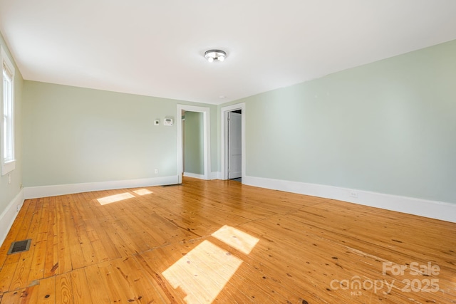 spare room featuring light wood-style flooring, visible vents, and baseboards