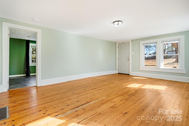 spare room with baseboards, visible vents, and hardwood / wood-style floors