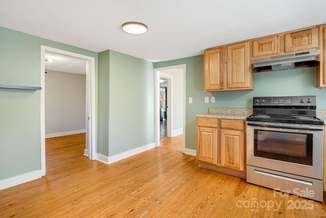 kitchen featuring electric stove, light countertops, light wood-type flooring, under cabinet range hood, and baseboards