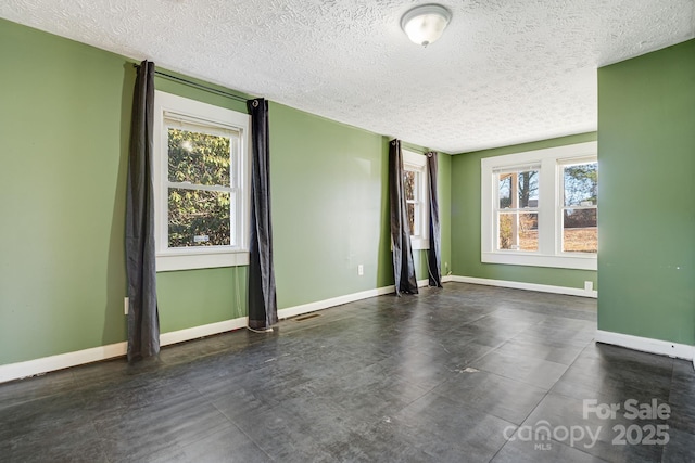 unfurnished room with visible vents, a textured ceiling, a wealth of natural light, and baseboards