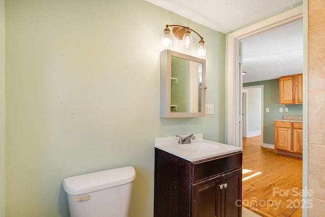 bathroom featuring baseboards, vanity, toilet, and wood finished floors