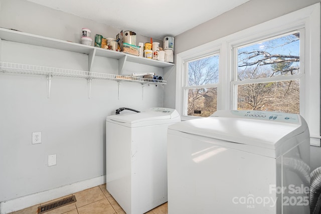 laundry area featuring light tile patterned floors, laundry area, washing machine and dryer, and visible vents