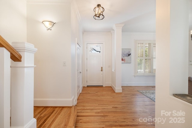 entrance foyer with ornamental molding, baseboards, and light wood finished floors