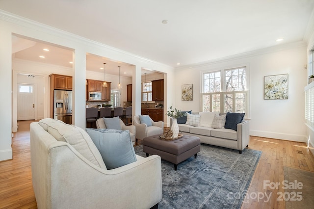 living room with light wood finished floors, crown molding, baseboards, and a wealth of natural light