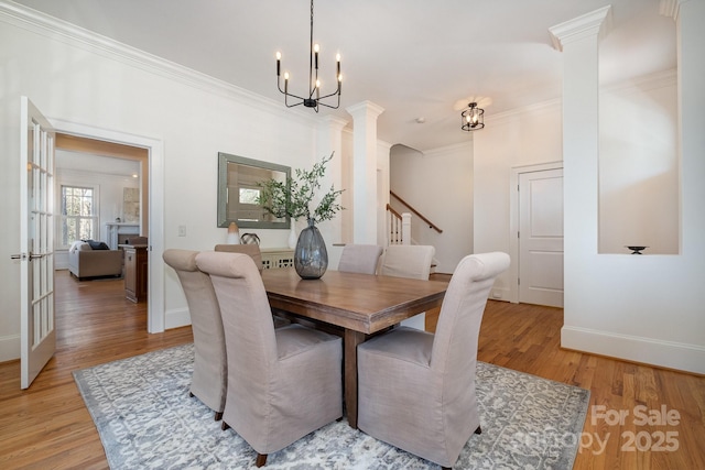 dining room with crown molding, baseboards, decorative columns, and light wood-style floors