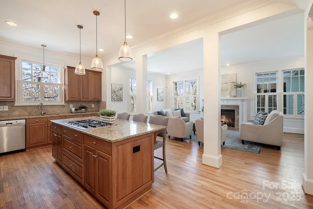 kitchen featuring a breakfast bar, a sink, open floor plan, appliances with stainless steel finishes, and brown cabinetry