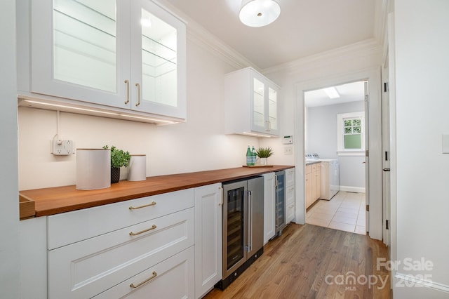 bar featuring light wood finished floors, wine cooler, washer / dryer, and crown molding