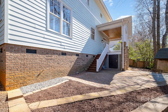 view of property exterior with a patio, stairway, crawl space, and fence