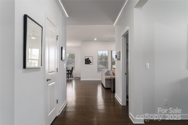 hallway featuring ornamental molding, dark wood finished floors, and baseboards