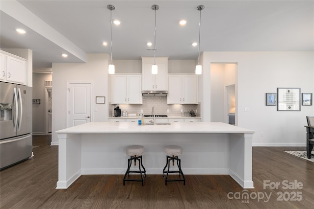 kitchen with light countertops, a sink, backsplash, and stainless steel fridge with ice dispenser