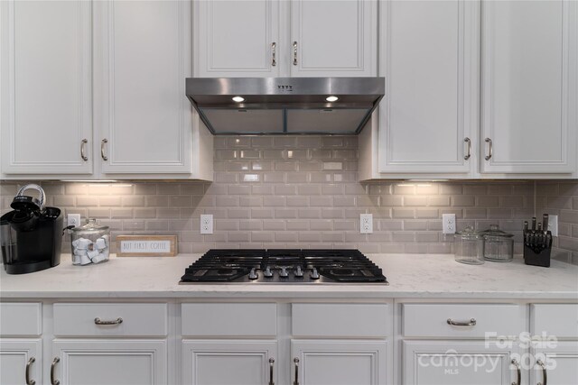 kitchen featuring stainless steel gas cooktop, tasteful backsplash, extractor fan, and white cabinets