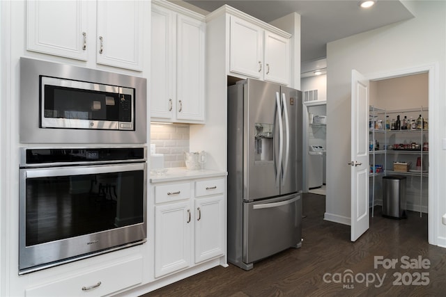 kitchen with dark wood-style flooring, white cabinets, light countertops, appliances with stainless steel finishes, and tasteful backsplash