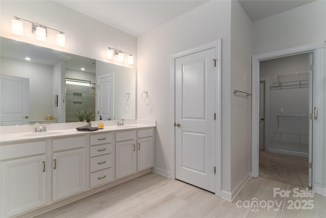 full bath featuring an enclosed shower, a sink, a spacious closet, and double vanity