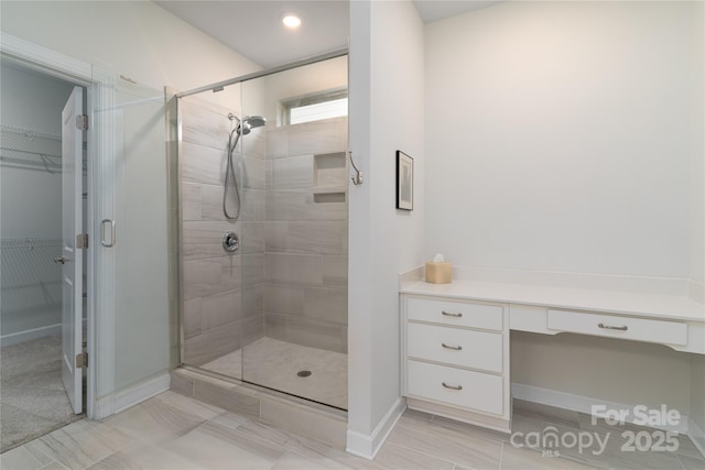 full bathroom with a walk in closet and a shower stall