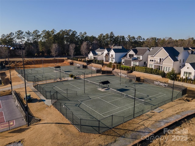 view of tennis court featuring fence and a residential view