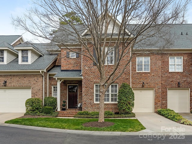 view of front facade with driveway, a shingled roof, and brick siding