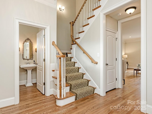 staircase featuring crown molding, baseboards, and wood finished floors