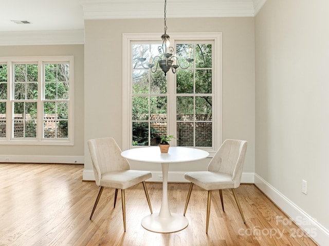 dining area featuring a chandelier, visible vents, crown molding, and light wood finished floors