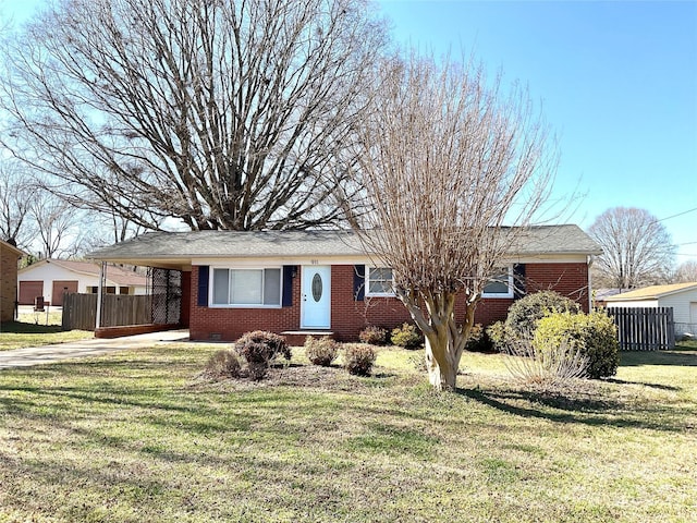 ranch-style home with a carport, brick siding, a front yard, and fence