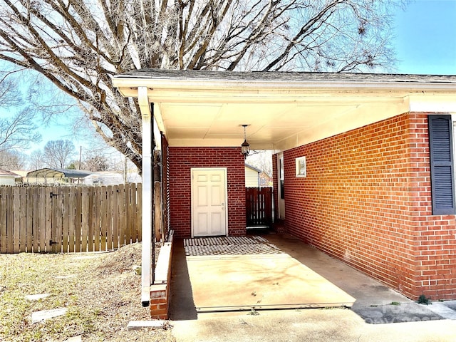 view of patio featuring driveway, fence, and a carport