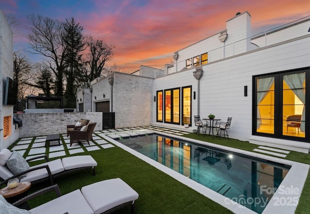 outdoor pool with a patio area, a lawn, and outdoor lounge area