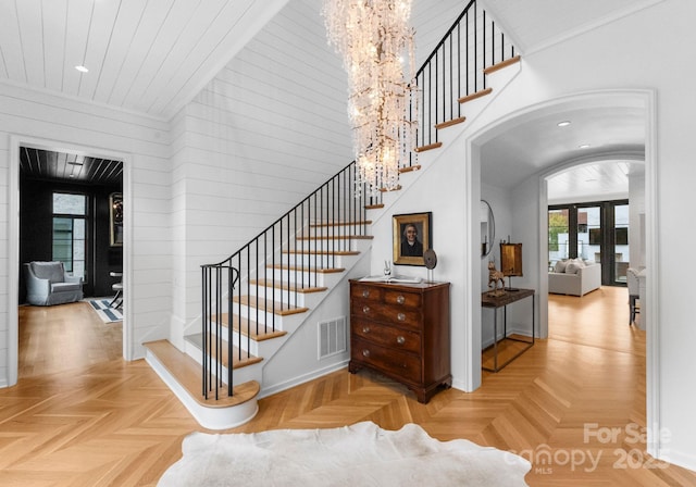 staircase with visible vents, baseboards, recessed lighting, arched walkways, and a notable chandelier