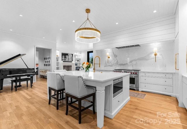 kitchen with light wood finished floors, stainless steel range, white cabinetry, and a sink