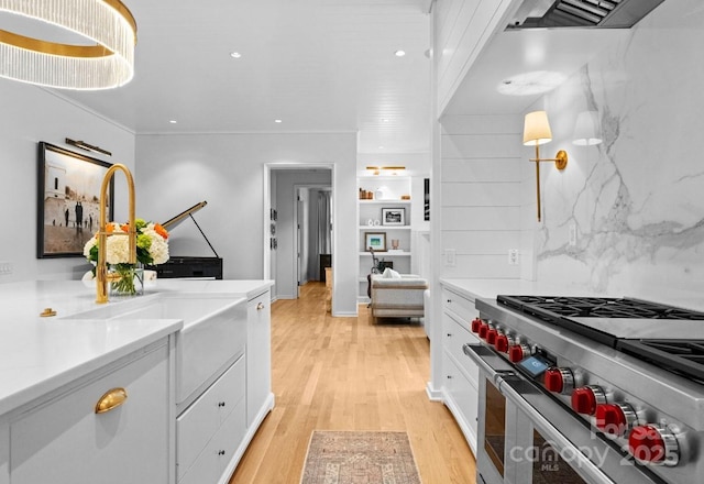 kitchen with white cabinetry, light wood-style flooring, light countertops, and stainless steel range