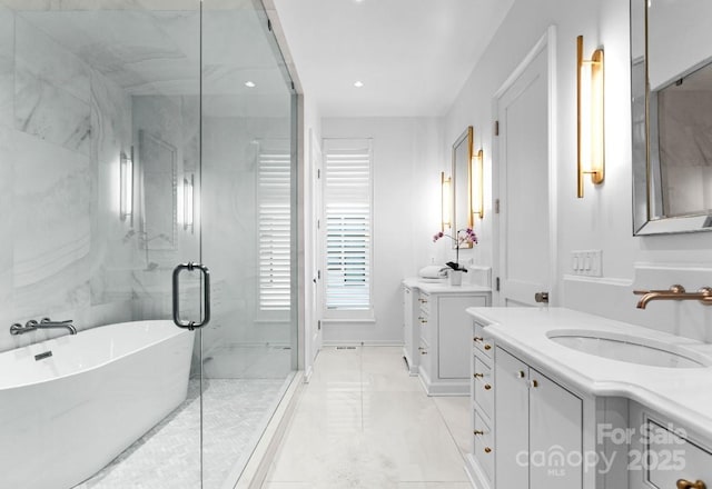 full bathroom featuring two vanities, a stall shower, a freestanding bath, a sink, and marble finish floor