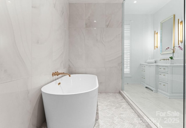 full bathroom featuring tile patterned floors, a soaking tub, vanity, and tile walls