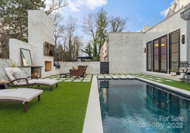 view of swimming pool featuring a fenced in pool, fence, an outdoor living space with a fireplace, a yard, and a patio area