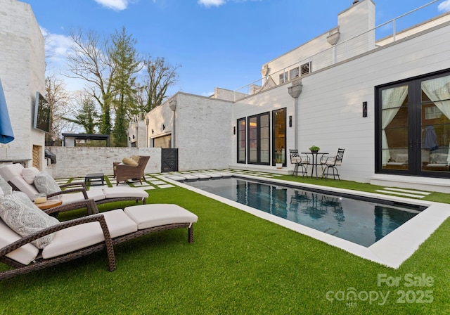 view of pool with a lawn, french doors, outdoor lounge area, a fenced backyard, and a patio area