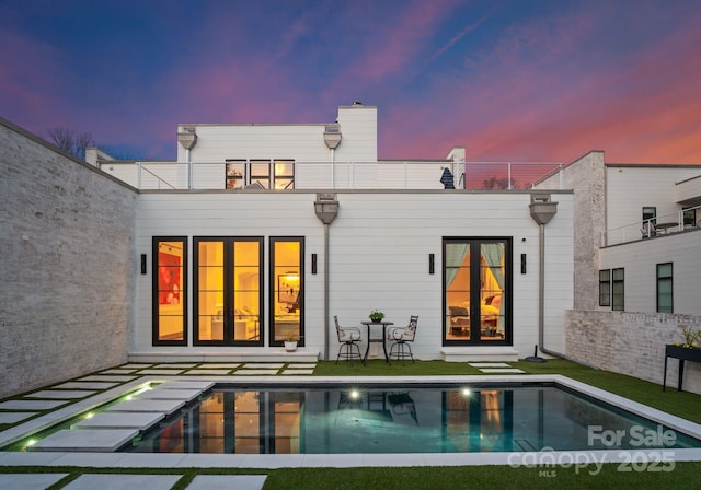 rear view of property featuring an outdoor pool and a balcony