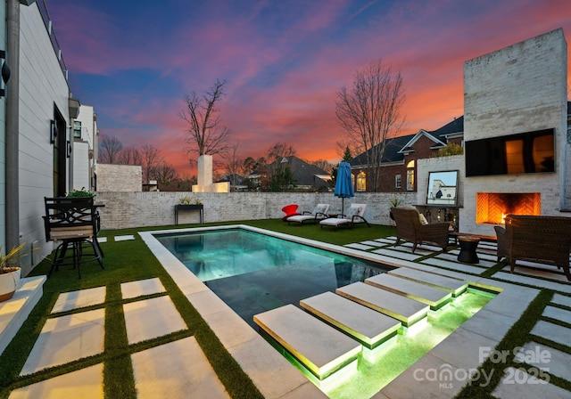 view of swimming pool featuring a patio area and an outdoor living space with a fireplace