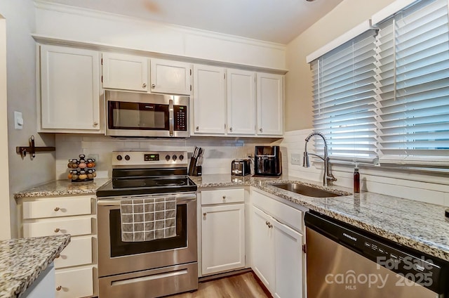 kitchen featuring decorative backsplash, white cabinets, appliances with stainless steel finishes, and a sink