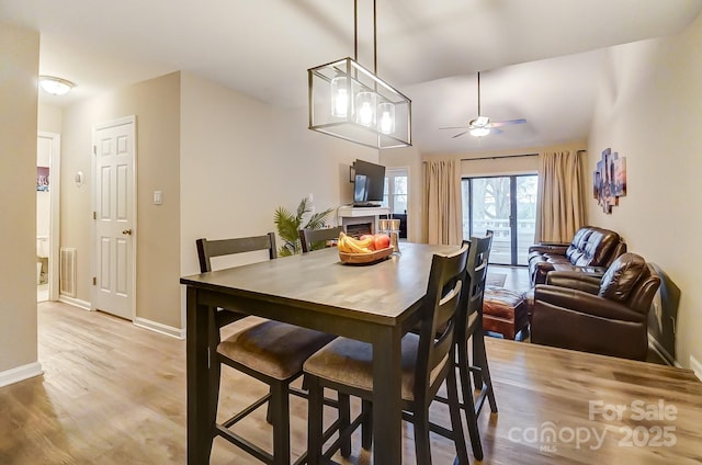 dining area featuring visible vents, light wood-style flooring, a fireplace, and baseboards