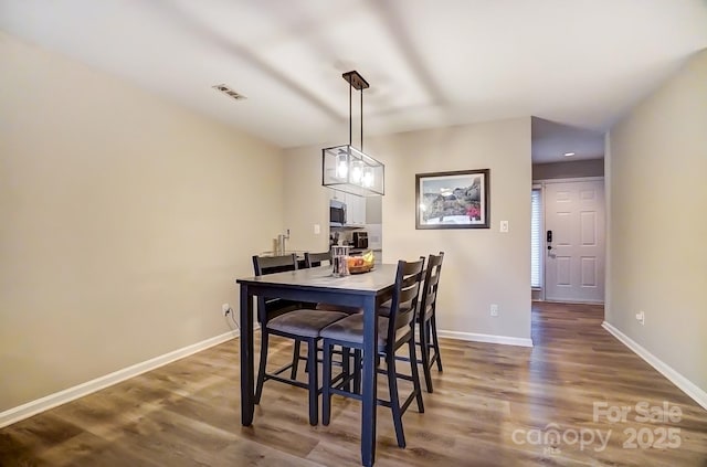 dining space with visible vents, baseboards, and wood finished floors