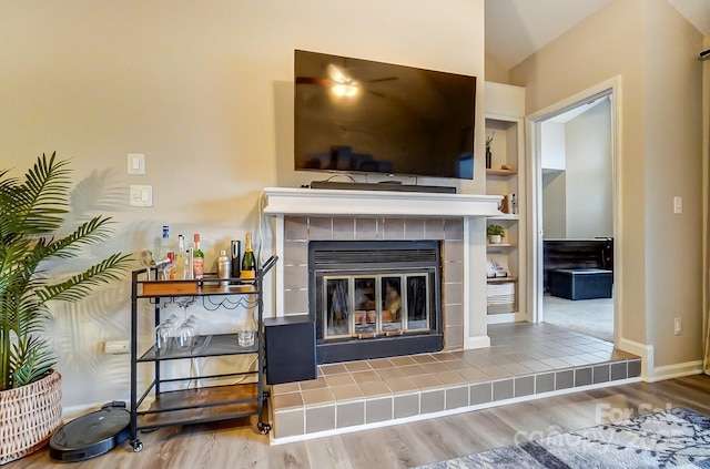 living room with baseboards, wood finished floors, and a tile fireplace