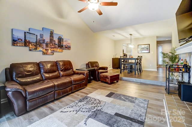 living area featuring lofted ceiling, wood finished floors, baseboards, and ceiling fan