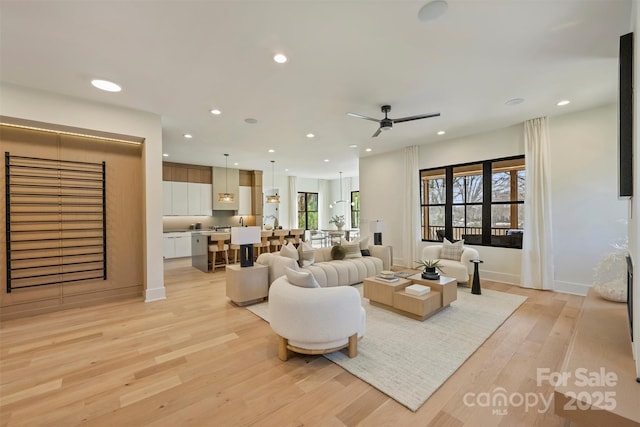 living room featuring a ceiling fan, recessed lighting, baseboards, and light wood finished floors