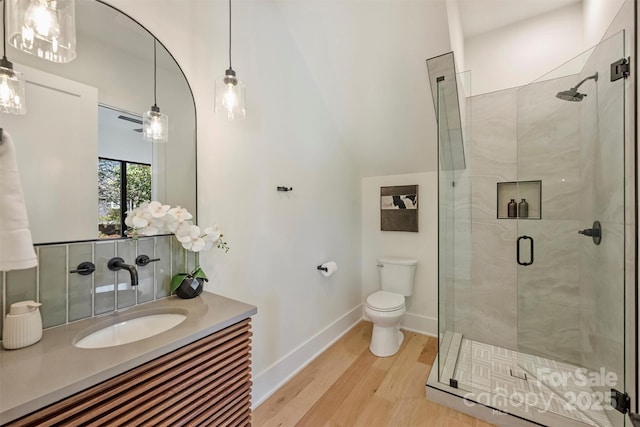 full bath featuring a stall shower, baseboards, toilet, wood finished floors, and vanity