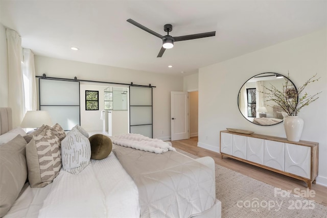 bedroom with a barn door, wood finished floors, and recessed lighting